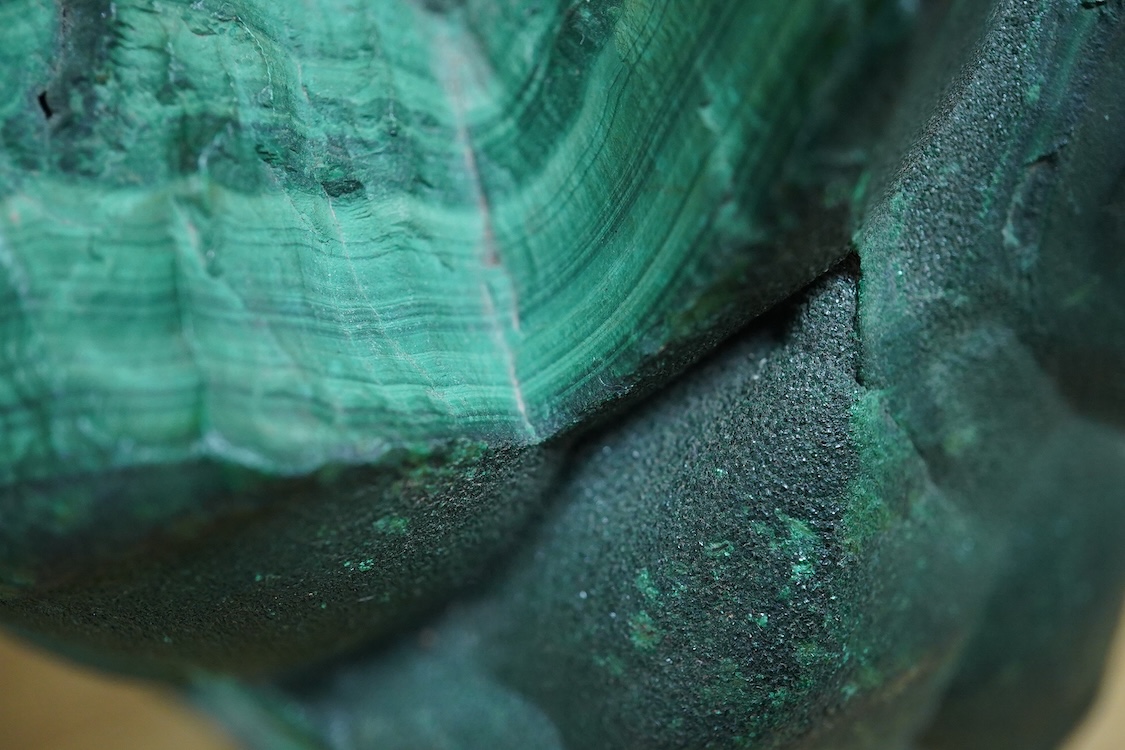 Two petrified wood ashtrays, a malachite rock, three onyx bowls, one with cover, and one other item, larger ashtray 17.5cm wide